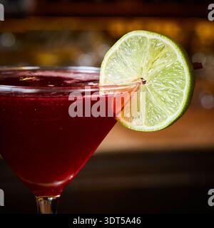 Cocktail cosmopolite rouge vif dans un verre à martini avec une garniture de citron vert frais Banque D'Images