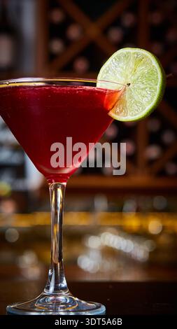 Cocktail cosmopolite rouge vif dans un verre à martini avec une garniture de citron vert frais Banque D'Images