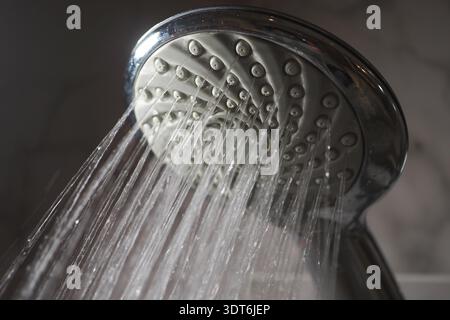 L'eau coule d'une pomme de douche dans un cadre de salle de bain Banque D'Images