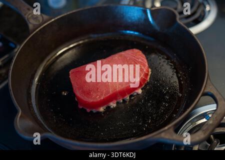 Steak de thon rose frit sur une poêle en fonte noire, scène de cuisson d'un concept de fruits de mer photo horizontale Banque D'Images