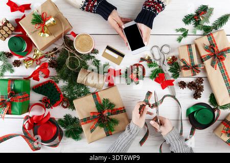 Emballage cadeau à la maison avec des décorations festives et des fournitures des fêtes disposées sur une table Banque D'Images