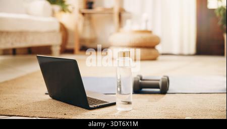 Vide, maison et ordinateur portable pour la configuration de l'entraînement, eau et haltères pour le fitness ou des conseils d'entraînement en streaming. Maison, tapis de yoga et technologie pour classe virtuelle dans Banque D'Images