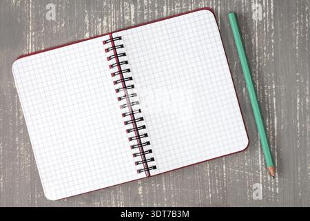 Vue de dessus du cahier en spirale et du crayon sur le fond en bois gris Banque D'Images