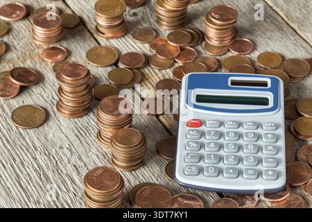 Calculatrice numérique et pièces empilées sur un fond en bois Banque D'Images