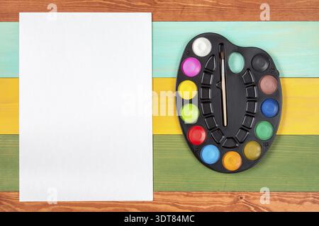 Peinture aquarelle et feuille de papier blanc sur fond en bois. Espace de copie Banque D'Images