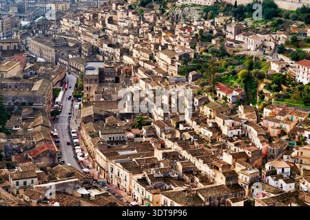 La vue aérienne montre le tracé de Modica en Sicile, avec de nombreux bâtiments en pierre et des rues étroites serpentant à travers le paysage. Banque D'Images