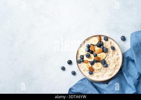 Bouillie d'avoine avec lait, bananes, noix et bleuets. Vue de dessus avec espace pour la conception. Banque D'Images