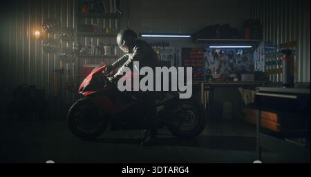 Male Rider en cuir noir veste se prépare pour la promenade de nuit. Une fois assis, l'homme adopte une position aérodynamique, les mains gantées prêtes à tourner le feu et apporter une vie puissante à la machine. Homme et machine. Ralenti. Banque D'Images