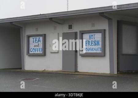 Kiosque de bord de mer à Littlehampton offrant thé, café et beignets frais chauds, panneaux bleus peints à la main sur le bâtiment blanc, côte couverte du Sussex ouest. Banque D'Images