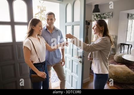 Agent immobilier remettant les clés de la maison à un couple heureux dans la porte Banque D'Images