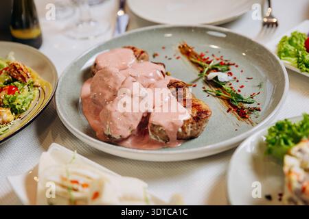 Médaillons de viande grillée à la sauce crémeuse servis sur l'élégante table du restaurant Banque D'Images
