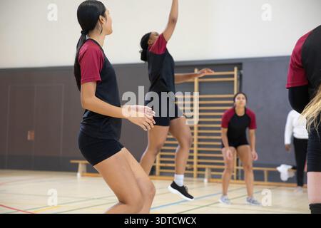 Athlètes féminines adolescentes diverses pratiquant dans le gymnase scolaire avec barres murales et kits d'équipe, espace de copie Banque D'Images