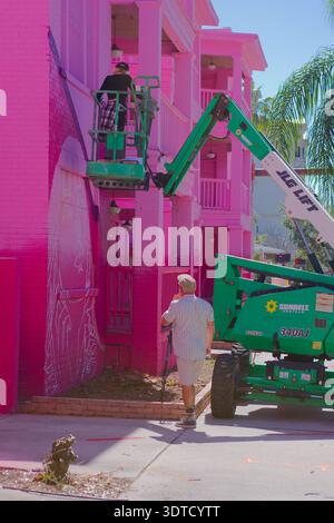Ouvrier peignant la peinture murale du bâtiment rose brillant de Green Boom Lift sur Sunny Street. Usage éditorial seulement 20 février 2026 produit Petersburg, FL USA. Travailleur sur un g. Banque D'Images