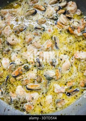 Cuisson des moules et des crevettes dans une sauce crémeuse Banque D'Images