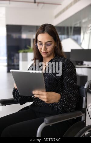 Jeune femme professionnelle occupée du moyen-Orient handicapée utilisant un fauteuil roulant Banque D'Images
