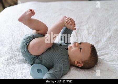 Bébé sur une couverture légère douce et jouant avec un jouet d'anneau empilable coloré. Banque D'Images