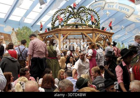 Tente de fête hacker-Pschorr avec des invités debout sur des bancs, devant le groupe de danse Schaeffler comme décoration, Oktoberfest Munich, Bavière, Allemagne Banque D'Images