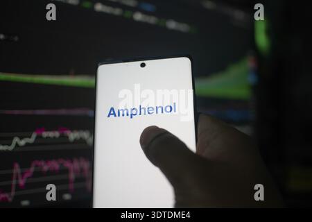 Un téléphone affichant le logo Amphenol devant les graphiques boursiers Banque D'Images