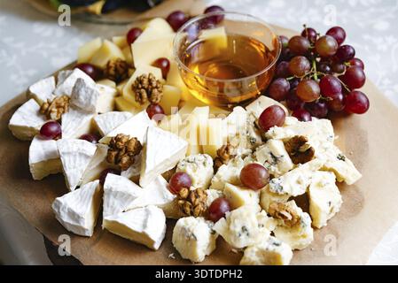 Assortiment de fromages et assiette de fruits. Une variété variée de fromages frais, fruits et noix présentés sur un grand plateau - un hors-d'œuvre sain idéal pour Banque D'Images