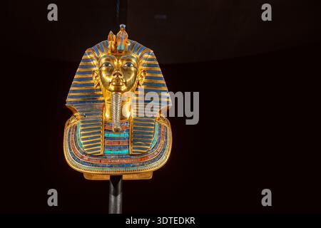 Masque funéraire doré de Toutankhamon isolé sur fond noir. Portrait emblématique du pharaon égyptien antique avec des rayures bleues et dorées et roy détaillé Banque D'Images