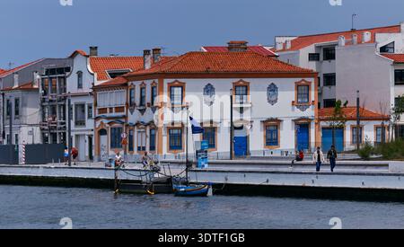 Aveiro, Portugal - 14 juin 2025 : bâtiments traditionnels en bord de mer avec des façades colorées et des bateaux de pêche le long de la rivière dans une ville côtière de Portug Banque D'Images