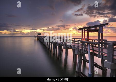 Éclair derrière rose et violet coucher de soleil sur la jetée de Naples sur la côte du golfe de Naples, Floride en été Banque D'Images