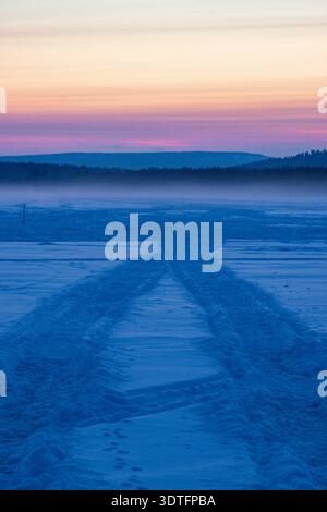 Coucher de soleil sur le lac Inari gelé avec des arbres couverts de neige en Laponie, Finlande près d'Ivalo Banque D'Images