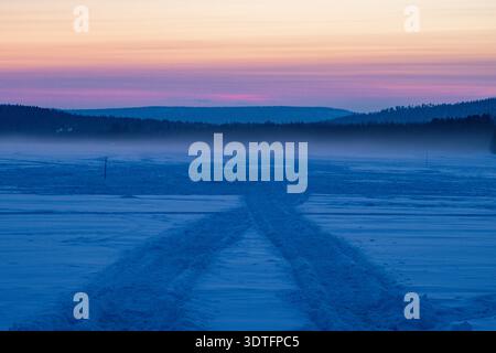 Coucher de soleil sur le lac Inari gelé avec des arbres couverts de neige en Laponie, Finlande près d'Ivalo Banque D'Images