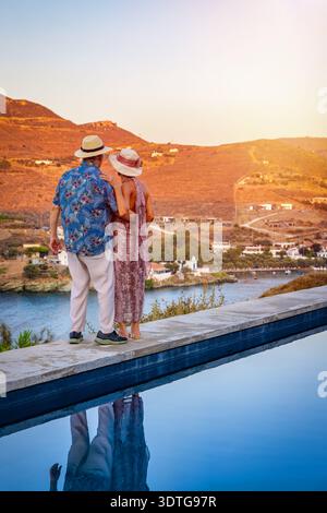 Un couple heureux et âgé en vacances se tient près de la piscine et profite de la vue sur le coucher du soleil Banque D'Images