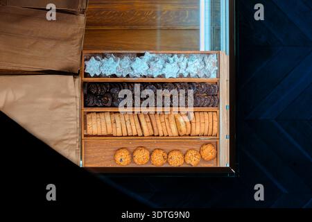 Une variété de friandises sucrées, y compris des biscuits en forme d'étoile, des biscuits au chocolat, des biscotti et des biscuits à l'avoine, sont soigneusement disposés dans une vitrine Banque D'Images