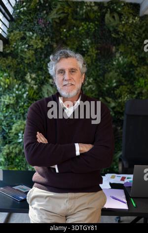 Homme senior confiant debout dans un bureau avec un jardin vertical, représentant le leadership et l'expérience Banque D'Images