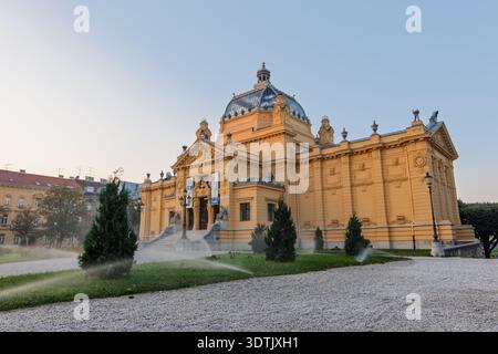 ZAGREB, CROATIE, 08.10.2018 :Grand Pavillon d'art à Zagreb avec architecture classique, statues en pierre, jardin paysager et façade ornée au crépuscule. Hist Banque D'Images