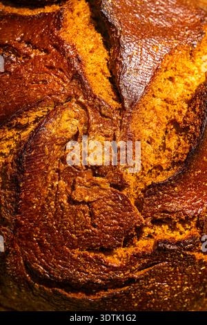 Image en gros plan capturant la texture complexe d'un pain artisanal fraîchement cuit, mettant en valeur sa riche croûte brun doré et ses miettes invitantes Banque D'Images