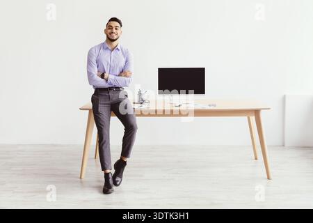 Homme se tient au bureau dans le bureau avec ordinateur pendant les heures de travail Banque D'Images