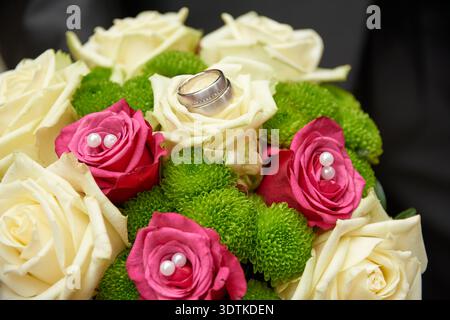 Gros plan d'un magnifique bouquet de mariage composé d'élégantes roses blanches et roses éclatantes, entrecoupées de chrysanthèmes verts luxuriants. Une paire de Banque D'Images
