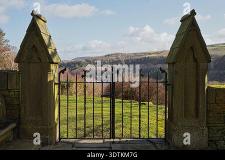 Des portes en fer forgé ornées d'embouts en fleur de lis sont situées entre des piliers de pierre gothique, donnant sur la vallée de Scammonden et le réservoir. Banque D'Images