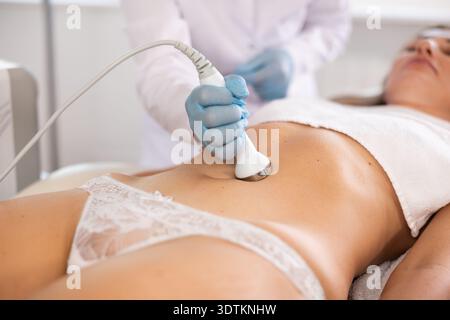 Patiente soumise à une procédure de cavitation ultrasonique sur le ventre à la clinique de médecine esthétique Banque D'Images