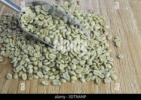 Les grains de café vert dans metal scoop sur la surface en bois vintage Banque D'Images