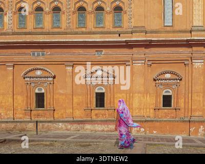 Femme indienne portant un sari coloré marche en face d'un monument Banque D'Images