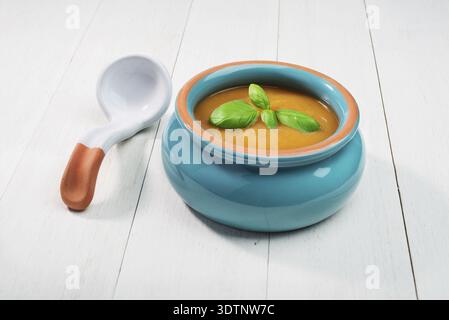 Soupe de citrouille fraîche dans un bol en céramique avec cuillère sur un vieux fond en bois Banque D'Images
