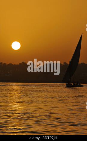 Coucher de soleil sur le Nil, Egypte avec un voilier felouque en silhouette Banque D'Images