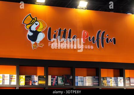 Signalisation orange et logo pour la maison Little Puffin Publishing affichés au-dessus des étagères des livres dans une librairie ou un salon du livre. Banque D'Images
