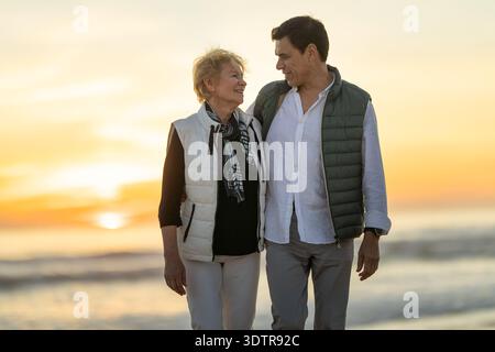 Couple appréciant une promenade romantique sur la plage pendant le coucher du soleil Banque D'Images