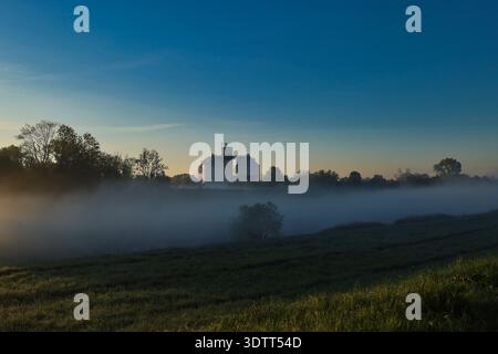 Vue matinale atmosphérique de la station d'épuration des eaux usées à Leipzig Rosental, avec une brume épaisse sur les champs sous un ciel clair de lever de soleil Banque D'Images
