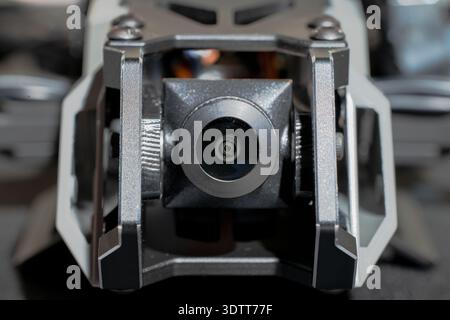 Vue détaillée d'un petit objectif de caméra de drone et de son système de stabilisation de cardan métallique, mettant en valeur l'ingénierie de précision et la technologie de pointe Banque D'Images