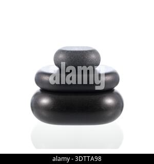 Pyramide de pierres zen de basalte noir pour massage chaud isolé sur blanc. Décoration spa ou welness Banque D'Images