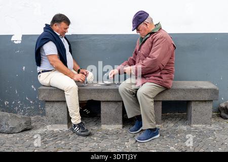 Hommes âgés jouant aux cartes ensemble dans la rue dans la vieille ville de Funchal, Madère, Portugal, capturant la vie locale quotidienne, l'interaction sociale et Banque D'Images