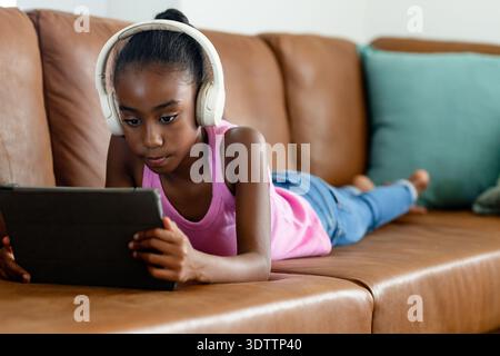 Tablette et écouteurs blancs reposent sur un canapé en cuir marron avec oreiller sarcelle dans le salon Banque D'Images
