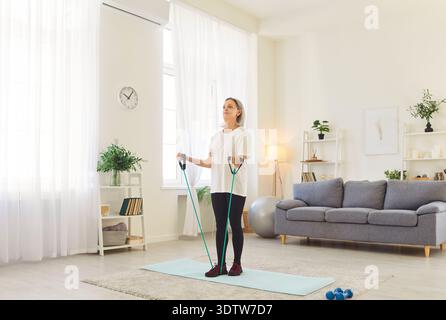 Active fit vieille femme senior sportive pratiquant, exercices d'élastique à la maison, étirements Banque D'Images