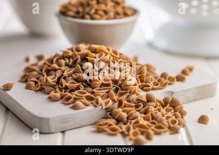 Pâtes de conchiglie à grains entiers sur une table blanche. Banque D'Images
